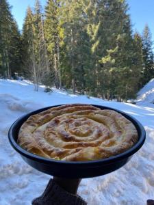 a person holding a pie in a bowl in the snow at Vila Dragana in Žabljak