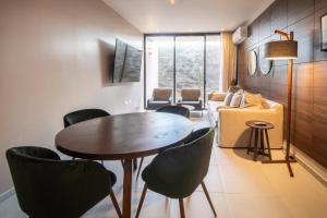sala de estar con mesa, sillas y sofá en PENINSULA STAYS 2 BR Designer Apartment & 200 MB FAST WIFI New Listing!, en Mérida