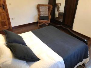 a bed with pillows and a chair in a room at Casa Fenteiras in Cangas de Morrazo