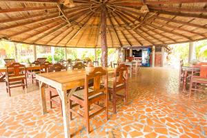 a wooden table and chairs under a large umbrella at Redwood Beach Resort in Mechapa