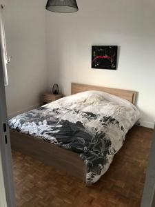 a bed with a black and white comforter in a bedroom at Appartement T3 Gilaldo in Anglet
