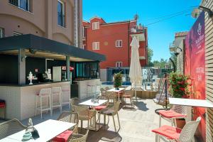 un patio al aire libre con mesas, sillas y una sombrilla en Hotel Stella Maris, en Vodice