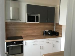 a kitchen with white cabinets and a microwave at Appartement T3 Gilaldo in Anglet