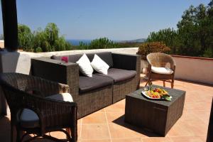 eine Terrasse mit Sofa, Stühlen und einem Tisch in der Unterkunft Hotel Micalosu in Cannigione