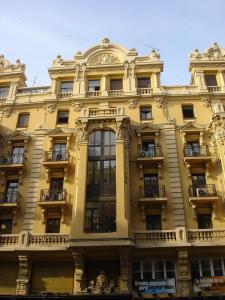 マドリードにあるHostal Avenidaの窓とバルコニー付きの大きな黄色の建物