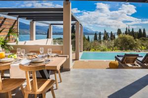 a dining room with a table and a view of a pool at Ionian Village in Lixouri