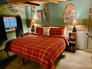 a bedroom with a bed with a red plaid blanket at Grunberg Haus Inn & Cabins in Waterbury