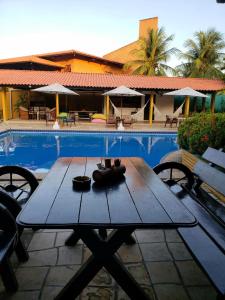 uma mesa de piquenique em madeira ao lado de uma piscina em Sunshine Cumbuco em Cumbuco