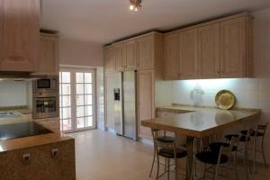 eine Küche mit Holzschränken und eine Insel mit Barhockern in der Unterkunft Casa do Castanheiro in Reboreda