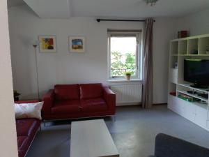 een woonkamer met een rode bank en een tv bij Vakantiehuis Arcadia in Zonnemaire