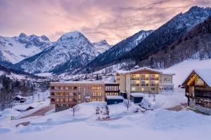 un edificio en la nieve con montañas en el fondo en Alpenhotel Zimba en Brand