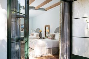 sypialnia z białym łóżkiem i szklanymi drzwiami w obiekcie Palihouse Santa Barbara w mieście Santa Barbara