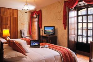 a hotel room with two beds and a television at Hotel Boutique Los Balcones in Cuenca