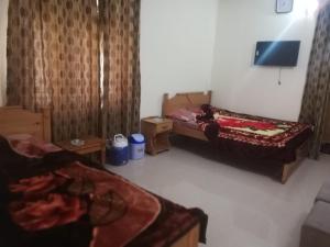 a bedroom with two beds and a tv in it at Riverside Hotel Kalam in Kārandūkai +22 photos
