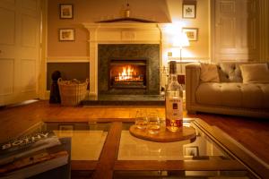 a living room with a fireplace and two glasses on a table at Craigellachie Lodge in Craigellachie