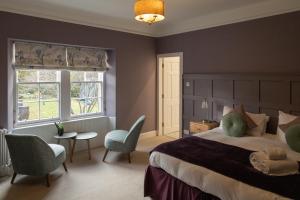 een slaapkamer met een groot bed en een tafel en stoelen bij Craigellachie Lodge in Craigellachie