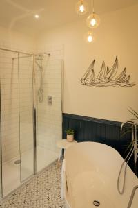 a bathroom with a tub and a shower with a sailboat on the wall at Craigellachie Lodge in Craigellachie