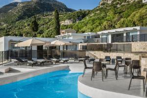 a hotel with a pool and chairs and a mountain at Erolidae Villas in Atsoupádhes