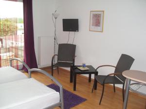 Zimmer mit Stühlen, einem Tisch und einem TV in der Unterkunft Casa Rose in Essen