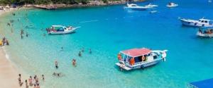 a group of people on a beach with boats in the water at Casa Jasmim arraial do cabo in Arraial do Cabo