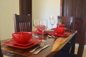 a wooden table with red plates and wine glasses at Hansa Departameto in Puerto Vallarta