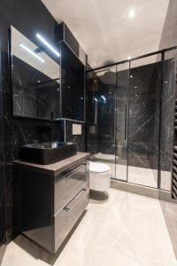 a black bathroom with a sink and a toilet at Beaubois in Paris