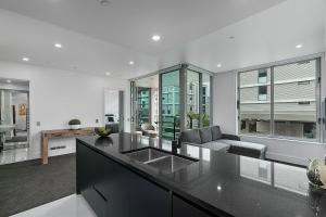 eine Küche mit Spüle und ein Wohnzimmer in der Unterkunft QV Stays Upscale Modern Viaduct Haven in Auckland
