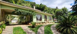 ein grünes Haus mit einer Terrasse und einem Hof in der Unterkunft Pousadinha Lá em Casa in Petrópolis