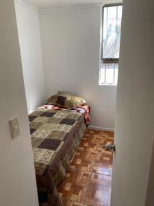 a small bedroom with a bed and a window at Departamento amoblado por día in Arica