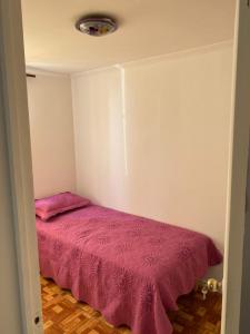 a bedroom with a bed with a pink blanket at Departamento amoblado por día in Arica
