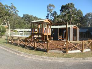 a playground in front of a house with a fence at Halls Gap Log Cabins in Halls Gap