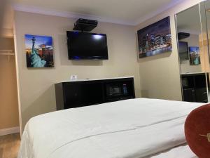 a bedroom with a bed and a flat screen tv at Relax Inn North Babylon in North Babylon