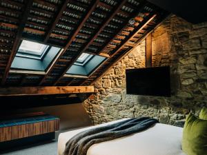 a bedroom with a stone wall with a bed and a tv at Moss Hotel in Hobart