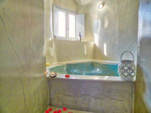 a bathroom with a jacuzzi tub with a window at Golden Stone Santorini Suites in Akrotiri