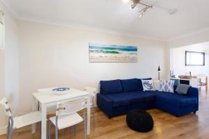 a living room with a blue couch and a table at Fremantle Sunset Studio Rottnest Island Views in Fremantle