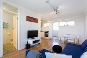 a living room with a blue couch and a tv at Fremantle Sunset Studio Rottnest Island Views in Fremantle