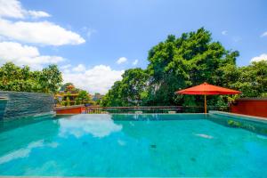 a large swimming pool with an umbrella and trees at Bali Ubud Harmony in Ubud