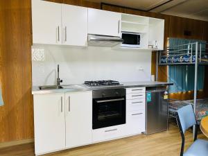 uma cozinha com armários brancos e um forno com placa de fogão em Mt Mittamatite Caravan Park em Corryong