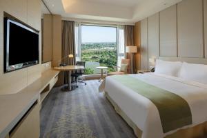 Habitación de hotel con cama grande y ventana grande. en Holiday Inn Nanyang, an IHG Hotel, en Nanyang