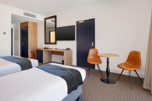 Cette chambre d'hôtel comprend deux lits, une table et des chaises. dans l'établissement Springs Newcastle, à Newcastle