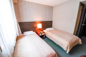 a hotel room with two beds and a lamp at Reisenkaku Hotel Ekimae in Fukuoka