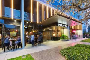 un gruppo di persone seduti ai tavoli fuori da un edificio di East Hotel and Apartments a Canberra