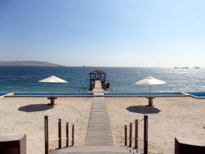 a dock with umbrellas on a beach next to the ocean at Paracas top tower beach front in Paracas
