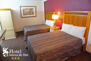 a hotel room with two beds and a lamp at Hotel Azteca de Oro Mexicali in Mexicali