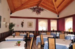 a dining room with white tables and chairs at Hotel Dolomiten in Dobbiaco