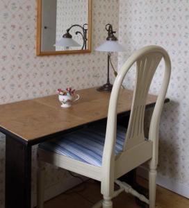 einem Holztisch mit einem weißen Stuhl und einer Lampe in der Unterkunft Karaby Gård in Kristinehamn