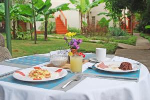 a table with two plates of food and a glass of orange juice at Hotel Posada Don Pantaleon in Managua