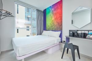 a bedroom with a white bed and a colorful wall at ibis budget Singapore Ametrine in Singapore
