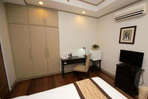 a bedroom with a desk and a bed and a television at Casa Pura Inn and Suites in Manila