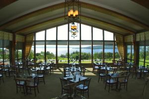 a dining room with tables and chairs and large windows at Silver Dart Lodge in Baddeck
